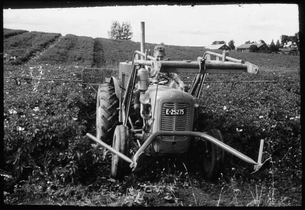 Avfotografert bilde av traktor som synes å ha frontmontert radrenser, og bakmontert sprøyteutstyr. Traktorføreren og stedet er ikke identifisert.