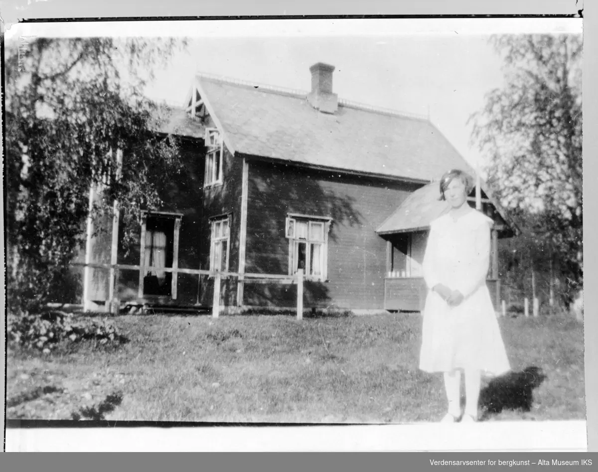 Konfirmant Randi Hapalathi på Bjørnstad Gård med hus i bakgrunn.