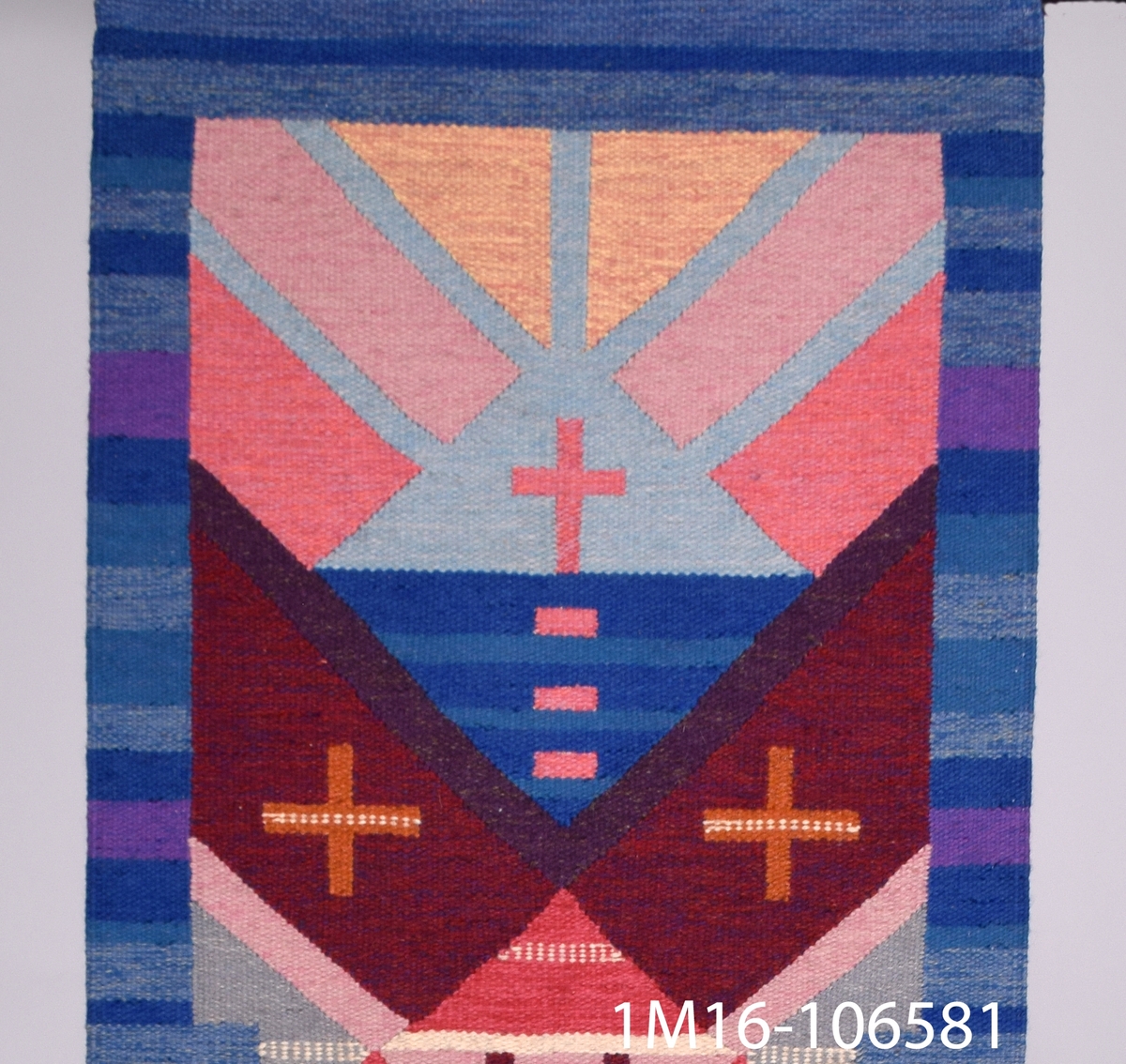 Väggtextil, vävd av Agda Österberg. På övre delen av vävnaden, ett kors.