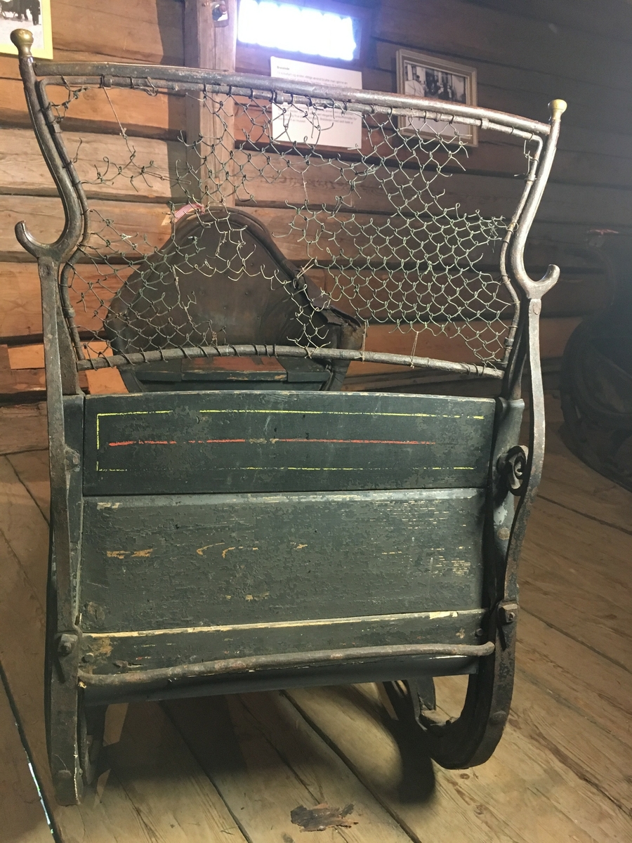 Spisslede av empiremodell fra før 1890. Forholdsvis stor, høy nettingskjerm foran. Romslig hovedsete trukket med skinn. Messingbelagt tomløper. Spesiell form på omramming på skvettskjerm. Smidde beslag, krussedull stiver av skjermen. Feste for skjeker (skjeker mangler). Sleden er reparert på museet. Personkjøretøy for hest til vinterføre brukt av kvinner og menn.