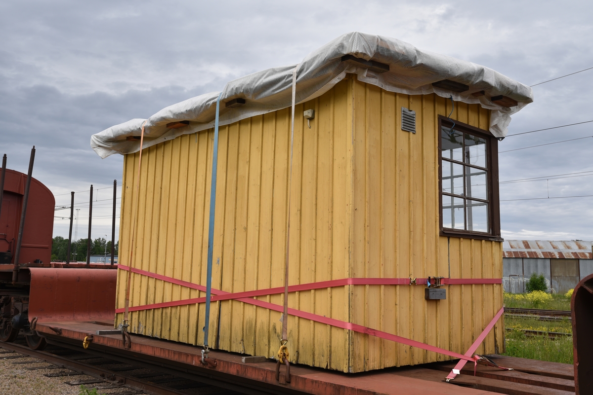 Hållplatskur från Tjunnaryd. Målad i ljusgul kulör med ljusgrå dörr, dörrfoder och fönsterfoder. Spröjsade fönster utmed hela framsidan, även på dörren, och delvis på sidorna.