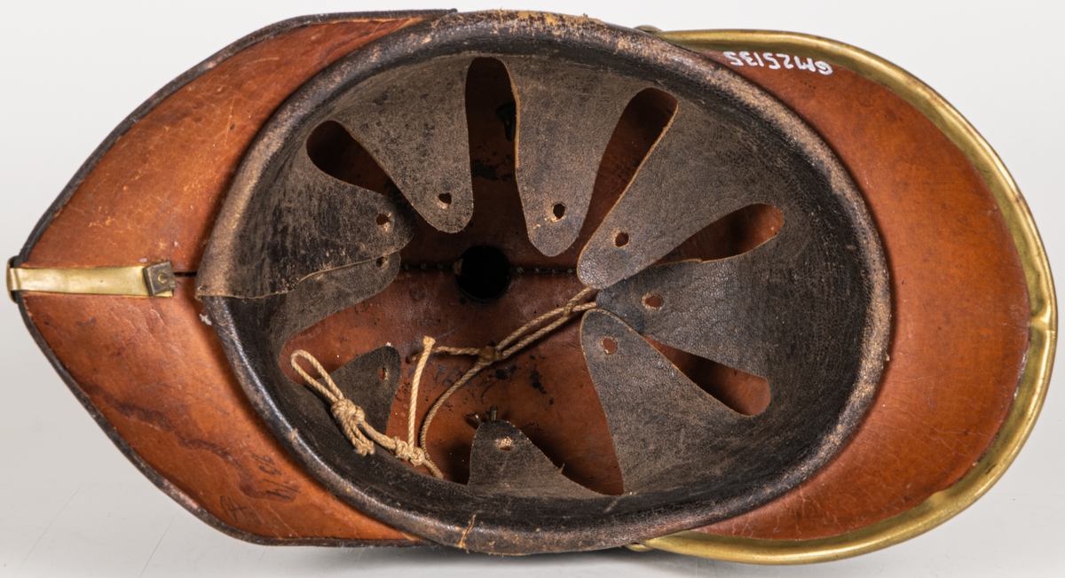 Kask m/1845 för infanteriet. Av pressat svartlackerat läder. hög välvd form med skärm och nackskycdd. Överst mässingspik med korsformat fäste. Skärmen mässingskantad. Framtill emblem i form av lilla riksvapnet i mässing. Hakremmar med fästen saknas. Spännbart "foder" av svart läder. Skrivet på nackskyddets insida. "Otto" samt "23 1/4".