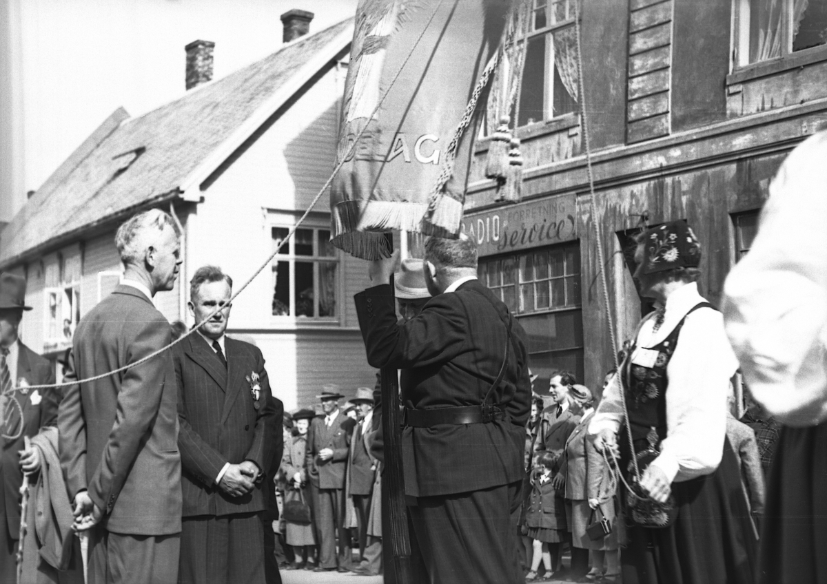 Opptog i Harstad. Mann med fanen til Norges Bondelag i midten.