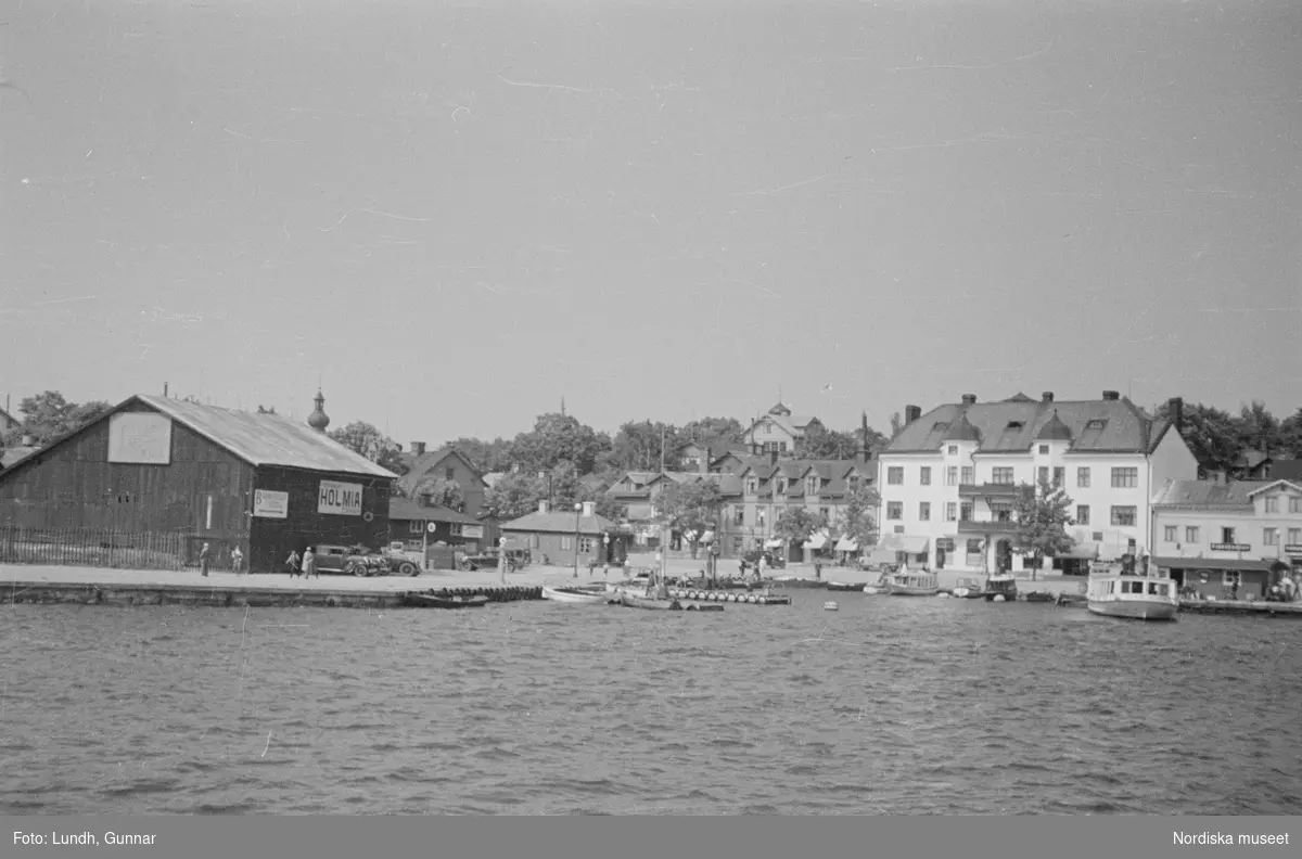 Motiv: Stockholm - Vaxholm;
Människor på en brygga med skylt "Edlunda", en segelbåt, människor på en brygga med skylt "Höganäs".

Motiv: Vaxholm;
Människor står på en brygga och en båt lägger till, en segelbåt, två män lyfter backar med flaskor på en brygga, folksamling vid möbler utställda på en grusplan (troligen en auktion).