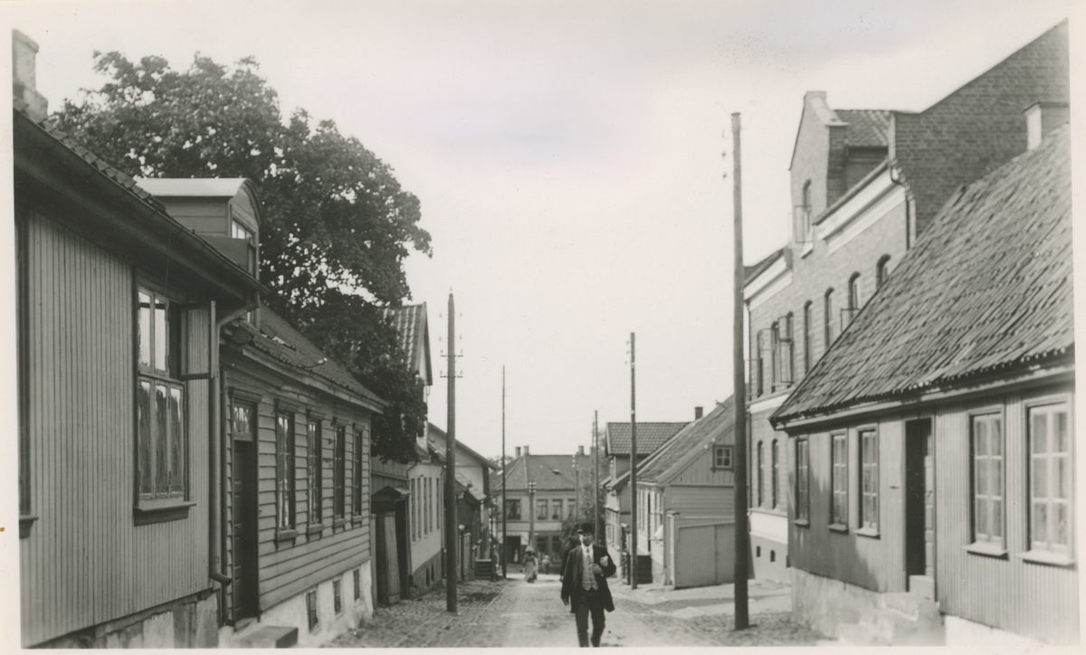 Fotograf har stått der det er øverst i Værlegata i dag.
Detaljer: På venstre side, Værlegata 4, 6, 8 osv. På høyre side Værlegata 5, 7, 11 osv.
Historikk: Bygget til høyre er "Agnaltgården" oppført 1825. Murgården oppført 1878, og gårdene nedenfor 180-årene. Til venstre oppført 1856 og de 2 neste gårdene ca. 1850.