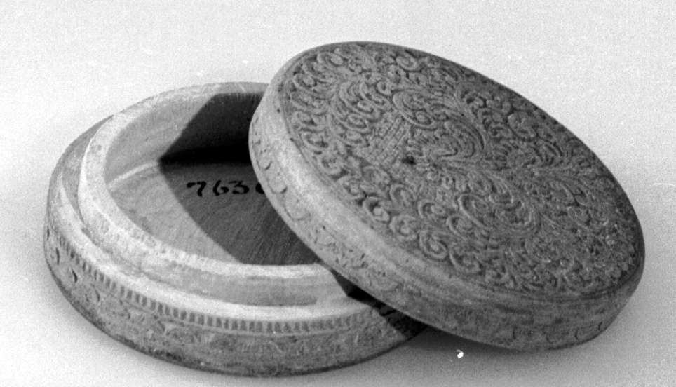 Rund eske av tre, med lokk. På lokket er det symmetriske treskjæringer av akantusmønster og rutenett, under esken er det konsentriske sirkler. På siden av esken og på siden av lokket er det border med konsentriske halvsirkler.