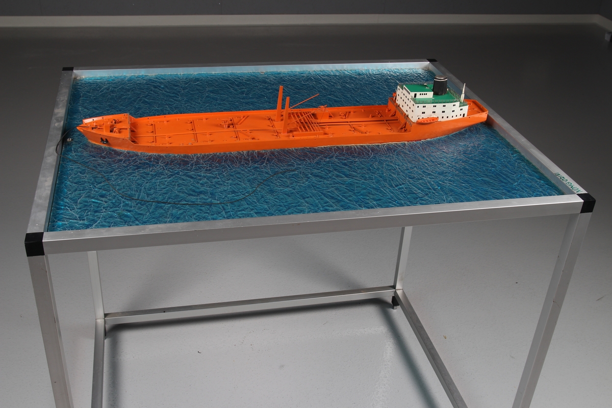 Modell av tankskip, såkalt bøyelaster - bygget i plast og montert på "sjø" av ruglet glassplate.