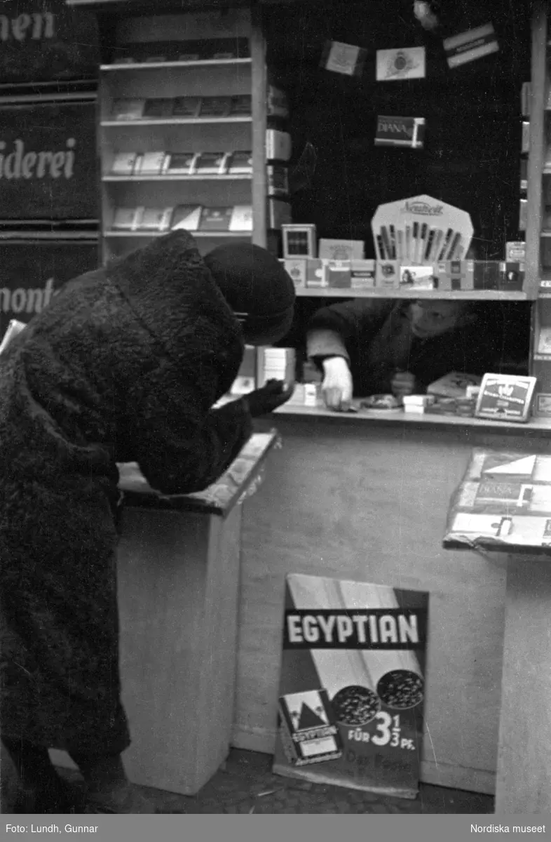 Motiv: Tyskland, Rankestrasse, Berlin, fröken Andersson, fru Rydelius;
Porträtt av två kvinnor som går på en stadsgata, en kvinna med svarta glasögon sitter i en port, stadsvy med fotgängare och en spårvagn.

Motiv: Tyskland, Berlin bl. a. Fredrichstrasse;
Skyltfönster med text "Gr. Mittagtisch! Kein Bedienungsgeld Kein Trinkzwang" och ett plakat uppsatt på fönstret, stadsvy med fotgängare och bilar, skyltfönster med text "Grog von Rum ....." "Fernsprechen", skyltfönster med text "Mittag u. Abend Gedeck 50" "Hier essen Sie besser und billiger" "Speise - Restaurant", skyltfönster med text "Gedecke bis 7 Uhr Abends 3 Gänge - 50 Grosse Auswahl."