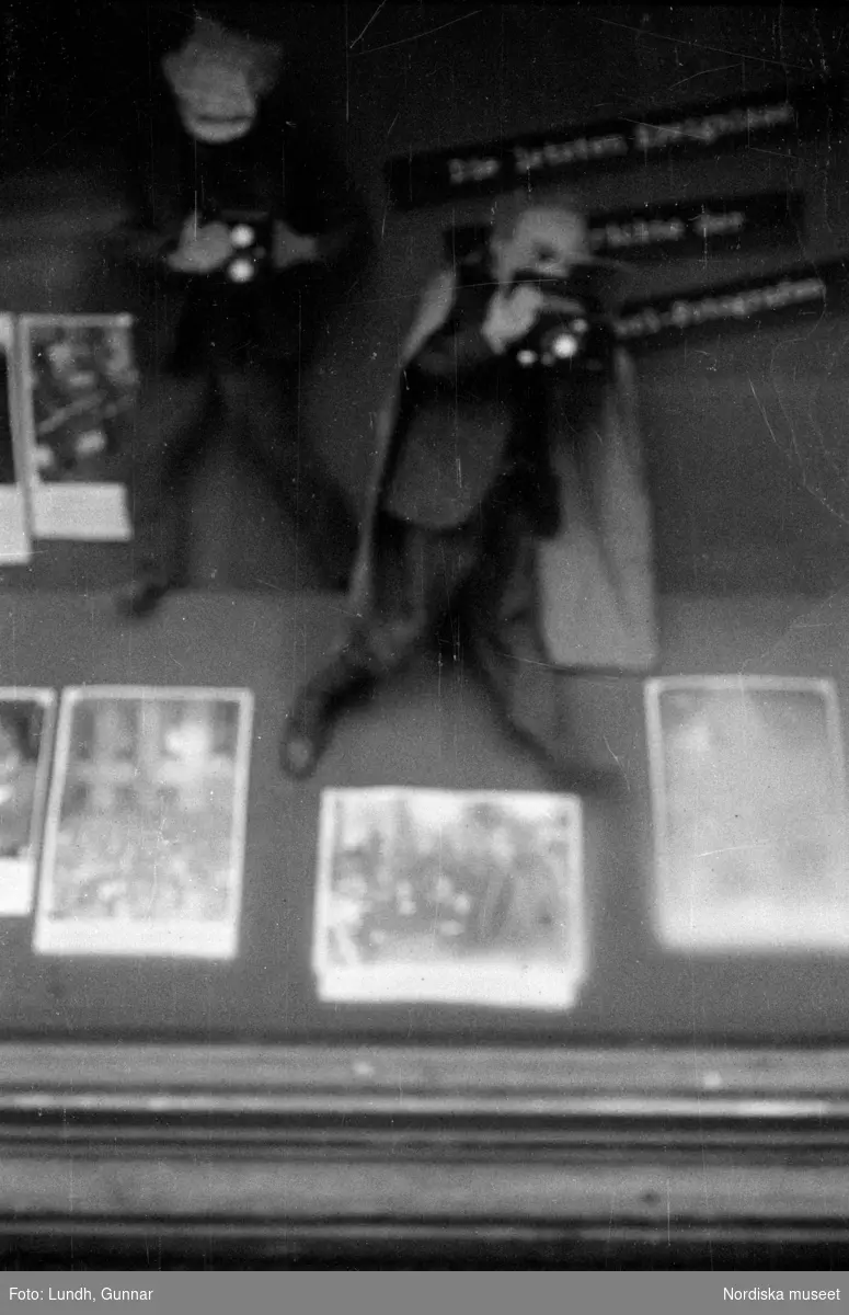 Motiv: Tyskland, Rankestrasse, Berlin, fröken Andersson, fru Rydelius;
Porträtt av två kvinnor som går på en stadsgata, en kvinna med svarta glasögon sitter i en port, stadsvy med fotgängare och en spårvagn.

Motiv: Tyskland, Berlin bl. a. Fredrichstrasse;
Skyltfönster med text "Gr. Mittagtisch! Kein Bedienungsgeld Kein Trinkzwang" och ett plakat uppsatt på fönstret, stadsvy med fotgängare och bilar, skyltfönster med text "Grog von Rum ....." "Fernsprechen", skyltfönster med text "Mittag u. Abend Gedeck 50" "Hier essen Sie besser und billiger" "Speise - Restaurant", skyltfönster med text "Gedecke bis 7 Uhr Abends 3 Gänge - 50 Grosse Auswahl."