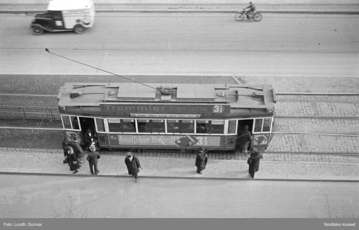 Motiv: Tyskland, Berlin bl. a. Friedrichstrasse;
Detalj av fasad med skylt "Zu vermieten ...", skylt "Warum kommen Sie nicht zu uns? ....", en man säljer tidningar.

Motiv: Tyskland, Vorwärts, Reinickendorf;
Gatuvy med människor vid en spårvagn, gatuvy med fotgängare - bilar och en hästdragen vagn, porträtt av en man "Apolant m fru", gatuvy med fotgängare.