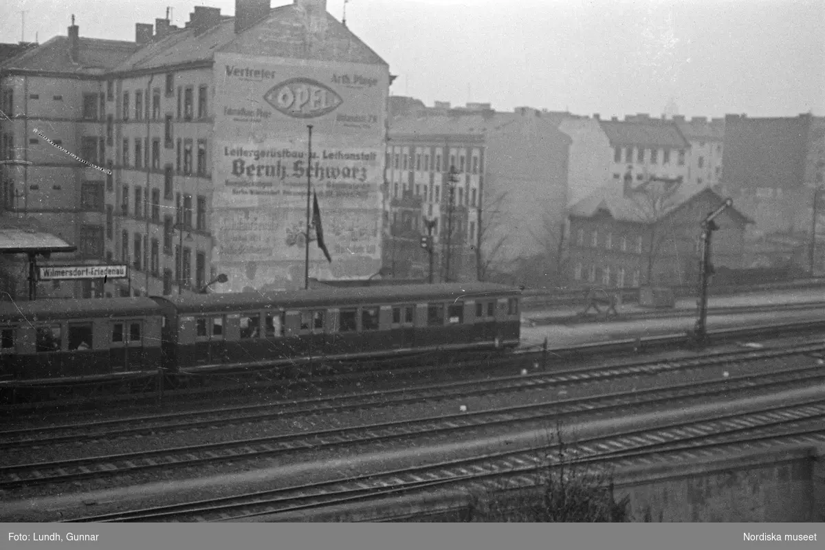 Motiv: Tyskland, Berlin, Untergrund, Friedman;
Ej kopierat.

Motiv: Tyskland, Berlin, Untergrund, Potsdamer-strasse, Potsdamer-platz;
Skylt "Pension 2 Etagen...", skyltfönster med två skyltdockor, en regnvåt gata, skylt "Zoolog. Garten", en man i fez håller upp en kanna och en kopp "Mocca Efti", skylt "Stimmüng" med en kvinna och en man som dricker cocktails, kvällsbild med belysning.