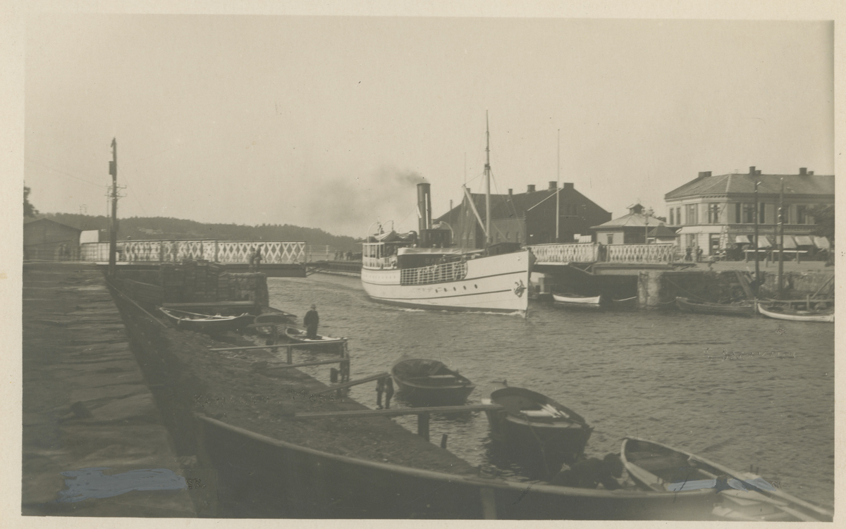 Kanalen.  Bastø II. Mellom 1929 - 1934. Postkort.

Fotograf har stått ved kanalparken på Jeløya.	
Detaljer:	Åpen svingbro, små robåter, Bastø II, Tollboden, Fiskebasaren, Jeløygata 1.
Historikk: Bastø II ble bygget ut i 1929, og omdøpt til "D/S Beta" i 1935.