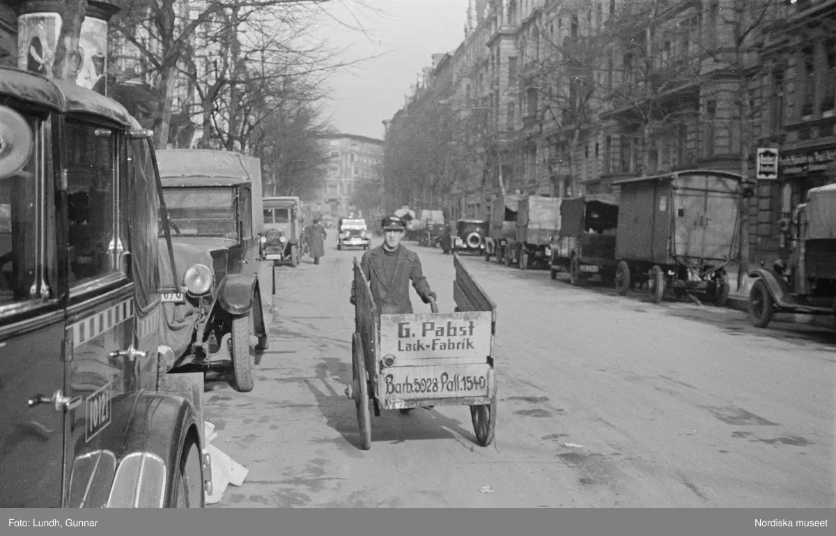 Motiv: Tyskland, Berlin;
Porträtt av en man "Tiller" som dricker ur ett glas.

Motiv: Tyskland, Berlin;
Utsikt från ett restaurangfönster över ett torg med torghandel, en man står vid ett försäljningsstånd med skylt "Sie husten nicht mehr!.....", gatuvy med en cyklist och en bil, gatuvy med bilar och en man som skjuter en kärra med text "G. Pabst Lack-Fabrik", skylt "Diese Villen sind im ganzen oder geteilt zu vermieten.....", grind med skyltar "Prof. Georg Klempener" "Professor Dr. A. Pinkuss", gatuvy med an man som samtalar med en kvinna, ett bord på gatan med böcker till försäljning, skylt "5 zimmer wohnung 1 etage auch geteilt per 1. april näheres b. wirt.", exteriör av byggnad med stor skylt på fasaden "Zu vermieten....", gatuvy med bilar - spårvagn - man med handkärra och en man som sopar gatan.
