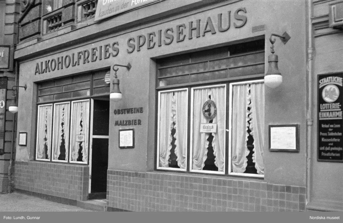 Motiv: Tyskland, Berlin;
Porträtt av en man "Tiller" som dricker ur ett glas.

Motiv: Tyskland, Berlin;
Utsikt från ett restaurangfönster över ett torg med torghandel, en man står vid ett försäljningsstånd med skylt "Sie husten nicht mehr!.....", gatuvy med en cyklist och en bil, gatuvy med bilar och en man som skjuter en kärra med text "G. Pabst Lack-Fabrik", skylt "Diese Villen sind im ganzen oder geteilt zu vermieten.....", grind med skyltar "Prof. Georg Klempener" "Professor Dr. A. Pinkuss", gatuvy med an man som samtalar med en kvinna, ett bord på gatan med böcker till försäljning, skylt "5 zimmer wohnung 1 etage auch geteilt per 1. april näheres b. wirt.", exteriör av byggnad med stor skylt på fasaden "Zu vermieten....", gatuvy med bilar - spårvagn - man med handkärra och en man som sopar gatan.