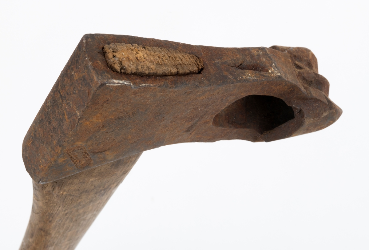 Øks - brukt til merking av fløtingstømmer i målings- og annammingsprosessen som foregikk langs vassdragene i overgangsfasen mellom vinter og vår, da tømmerstokkene etter måling formelt skiftet eier - fra skogeieren som hadde organisert hogst og framkjøring til sagbruk eller treforedlingsbedrift, som kjøpte tømmeret med sikte på videre bearbeiding til produkter som var salgbare på et større marked. 

Øksehodet (den smidde delen) er 14,2 centimeter høyt fra eggpartiet til nakken. Nakkedelen er 7,9 centimeter lang, 2,5 centimeter bred bakerst og 2,3 centimeter bred foran. Øksenakken er noenlunde plan i lengderetningen. På venstre side av den nedre delen av øksehodet (bladet) er det utsmidd en 3,5 centimeter høy «sko» med profilert, fasslipt egg. Denne eggen ble slått inn i yteveden på fløtingsvirket, der den etterlot seg en profilert forsenkning, et symbol som tjente som sorteringsgrunnlag ved lenseanleggene i den nedre delen av vassdraget. På denne øksa minner eggprofilen om omrisset av ei krone. På høyre side av øksehodet finner vi smedstempelet «K. KNUDSEN  MJØNDALEN» samt avbildninger av medaljer denne produsenten hadde oppnådd på utstillinger. Øksehodet er rustent og stempelet er vanskelig lesbart.

Denne øksa har et cirka 60 centimeter langt, noenlunde rett treskaft. Som økseskaft flest er det bredest i høyderetningen og smalest i bredderetningen i den fremre enden, der den er skjeftet. Den bakre delen av skaftet er mer rundoval. Den fremre skaftenden er kilet med en trekile som skulle redusere faren for at øksa løsnet fra skaftet under merkingsarbeidet. Det forkortete firmanavnet «KELL-PARTINGTON» er påført den venstre sida av skaftet (sett i øksebrukerens perspektiv) ved hjelp av svijernstempel. Dette indikerer at øksa har vært brukt til å merke tømmer som ble innkjøpt på vegne av The Kellner Partington Paper Pulp Co. Lim., et engelsk selskap som fram til 1918 eide Borregaard-fabrikken i Sarpsborg. Navnet fortsatte å figurere på merkekartene også etter at Borregaard fikk norsk eierskap, jfr. «Merkekart 1953 for Glommen» i Julius Nygaards skogalmanakk 1954. 

Litt generell informasjon om bruken av merkeøkser i skogbruket finnes under fanen «Opplysninger».