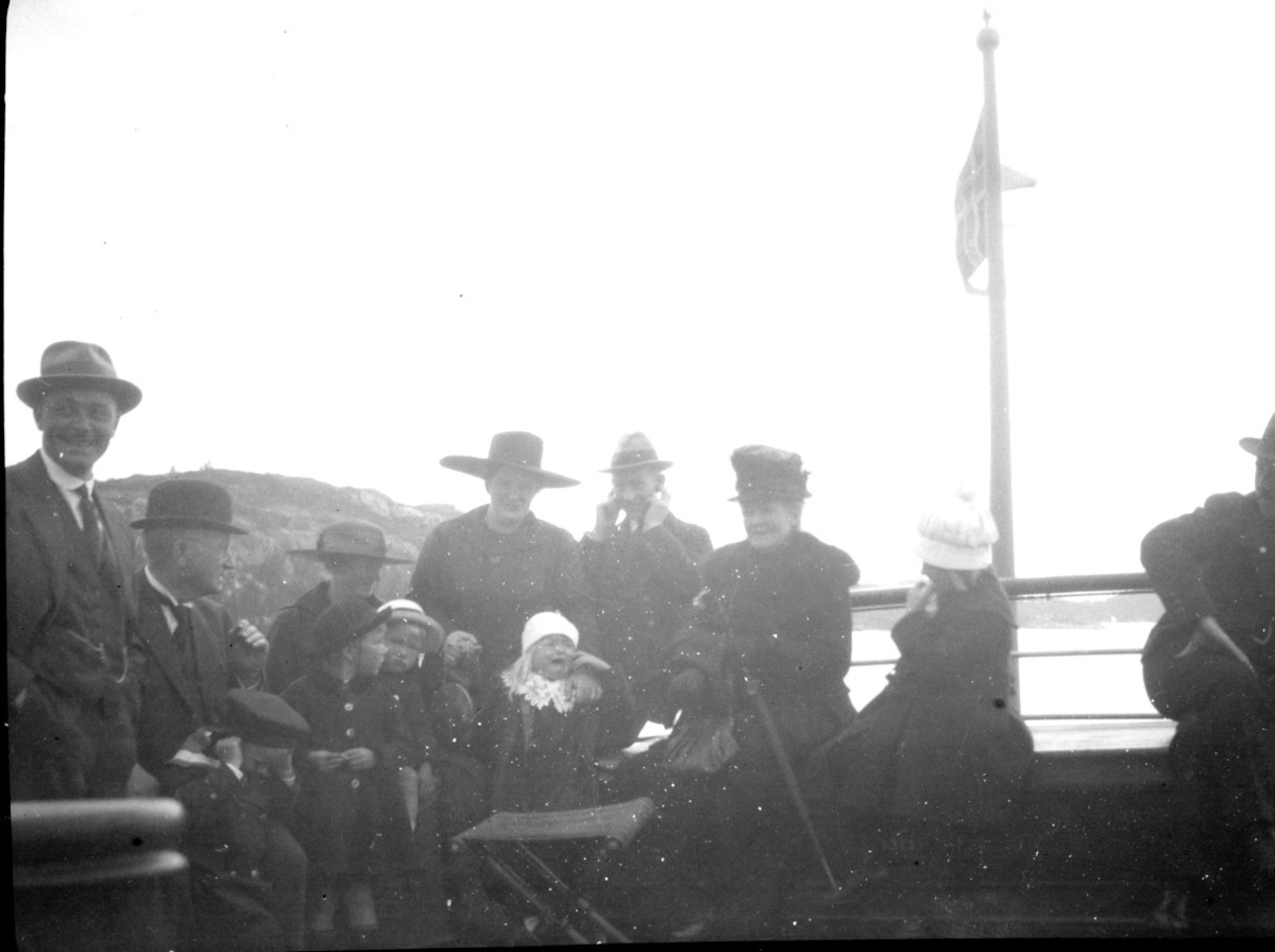 Familier ombord i kystruta. Et barn gråter så høyt at både en voksen og et barn holder for ørene. ca. 1900 -1910