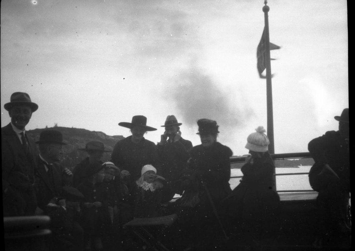 Familier ombord i kystruta. Et barn gråter så høyt at både en voksen og et barn holder for ørene. ca. 1900 -1910