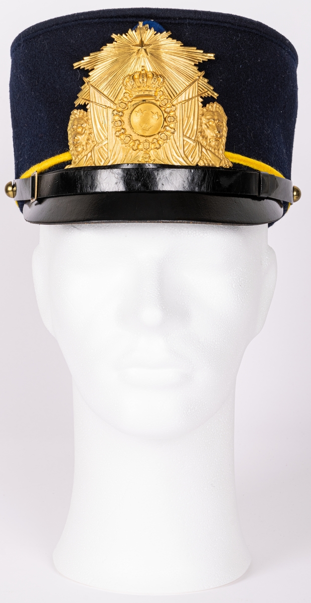 Mössa, uniformsmössa, blå med stor mässingsbricka, lilla riksvapnet omgivet av lejon, flaggor och med kungl. krona ovanför samt 5-uddig stjärna med strålar. Överst plymfäste med tagelplym. M/1899.