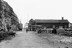 Motiv från varvsområdet Karlsro i Norrköping. Anläggningen till höger uppfördes omkring 1917 som maskinhall för Norrköpings Varfs- & Werkstads AB. Vid tiden för bilden står byggnaden inför rivning på grund av brandrisk och reorganisering av varvsområdet inför kommande fartygsproduktion.