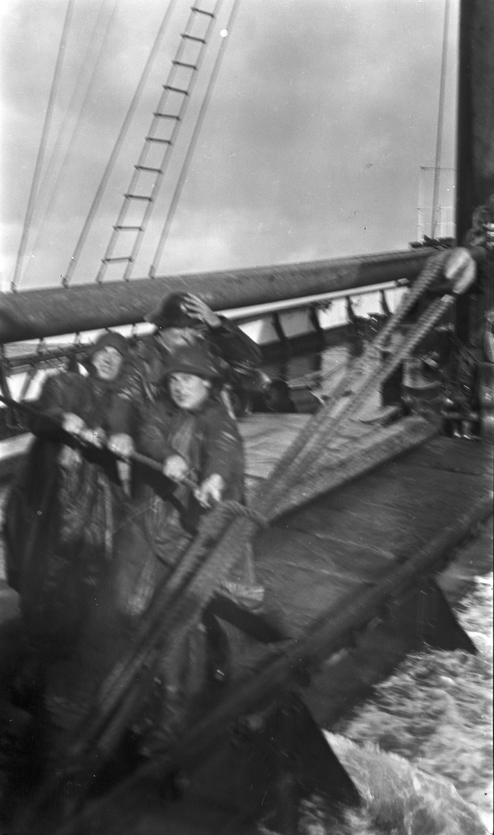 Tre menn i oljehyre haler i reip om bord på DS STORFOND. Brottsjø skyller over dekk.