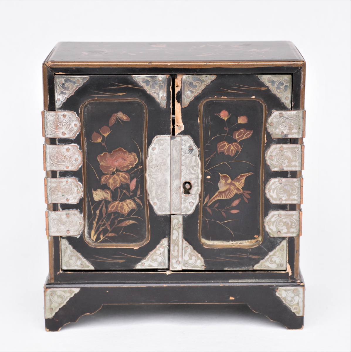 Lite skap med tre skuffer til dukkehus. Fin snekkering, svartmalt, metallbeslag og dekorert med fugler og blomster på alle sider. Svart, gull, sølvfarget.