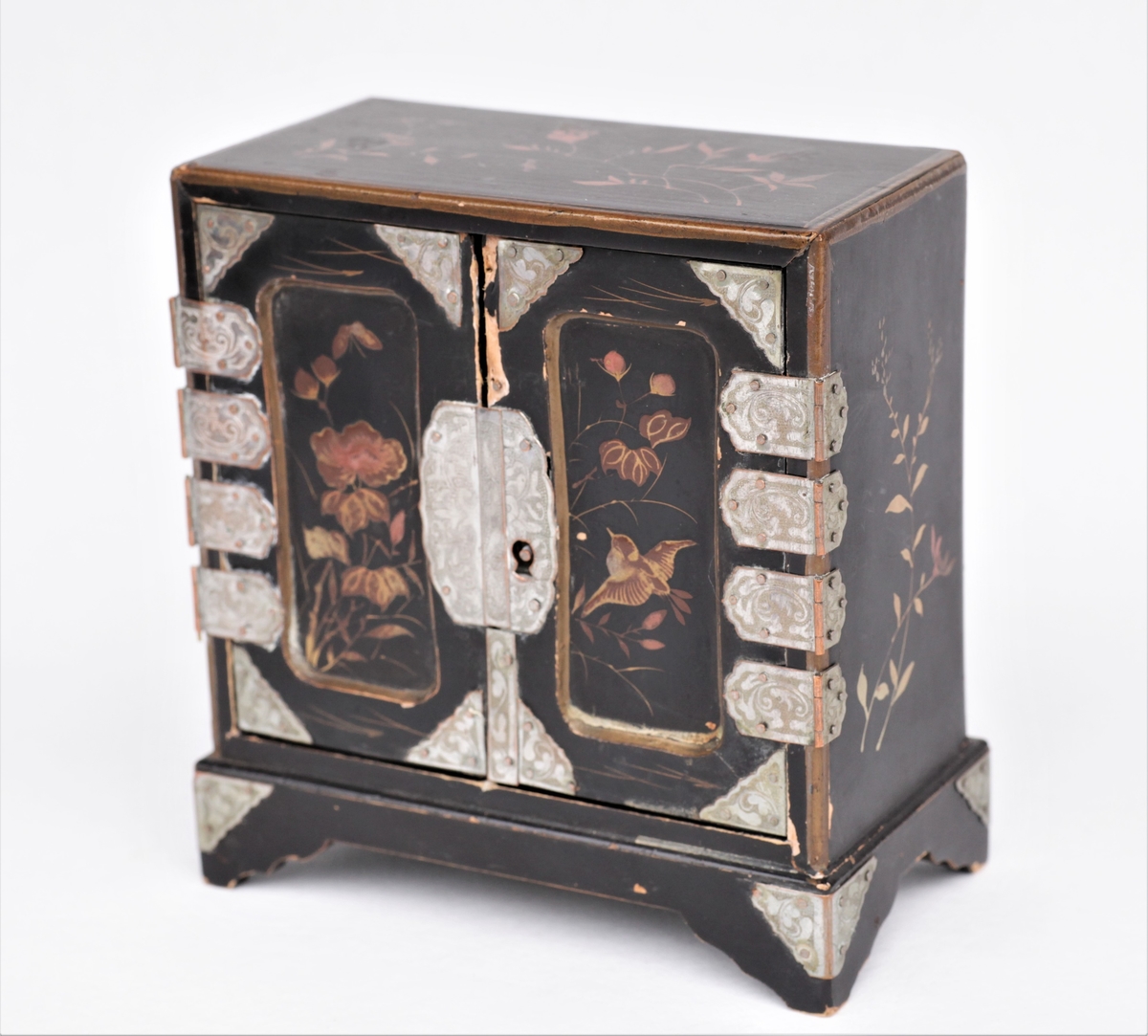 Lite skap med tre skuffer til dukkehus. Fin snekkering, svartmalt, metallbeslag og dekorert med fugler og blomster på alle sider. Svart, gull, sølvfarget.