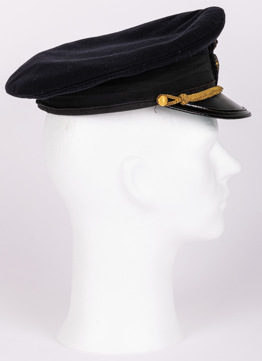 Skärmmössa m/30 för flygvapnet.
Av mörkblått ylletyg (gabardin) med svartlackerad skärm (undersidan ljusgrön). Svart textilband runt mössans nederdel. Kullen cirkelrund, platt och med större diameter. Dess styvnader är borttagna. Flygemblek av broderad guldtråd. Hakrem av flätad guldtråd (m/39), fäst med två små kronknappar. Vitt linnefoder. Svettremmen märkt "HF". etikett i kullen "KÖRSNÄR Lundbladhs HÄLSINGBORG"