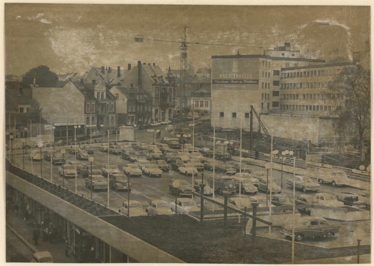 Nedre torv (Domustorvet). 17. oktober 1964.

Fotograf har stått i en bygning i Th. Petersons gate.
Detaljer:	Domustorvet, Torggata, baksiden av Dronningens gate 1.
Historikk: Parkeringstorvet sto ferdig i 1964, før oppføringen av Domusbygget.