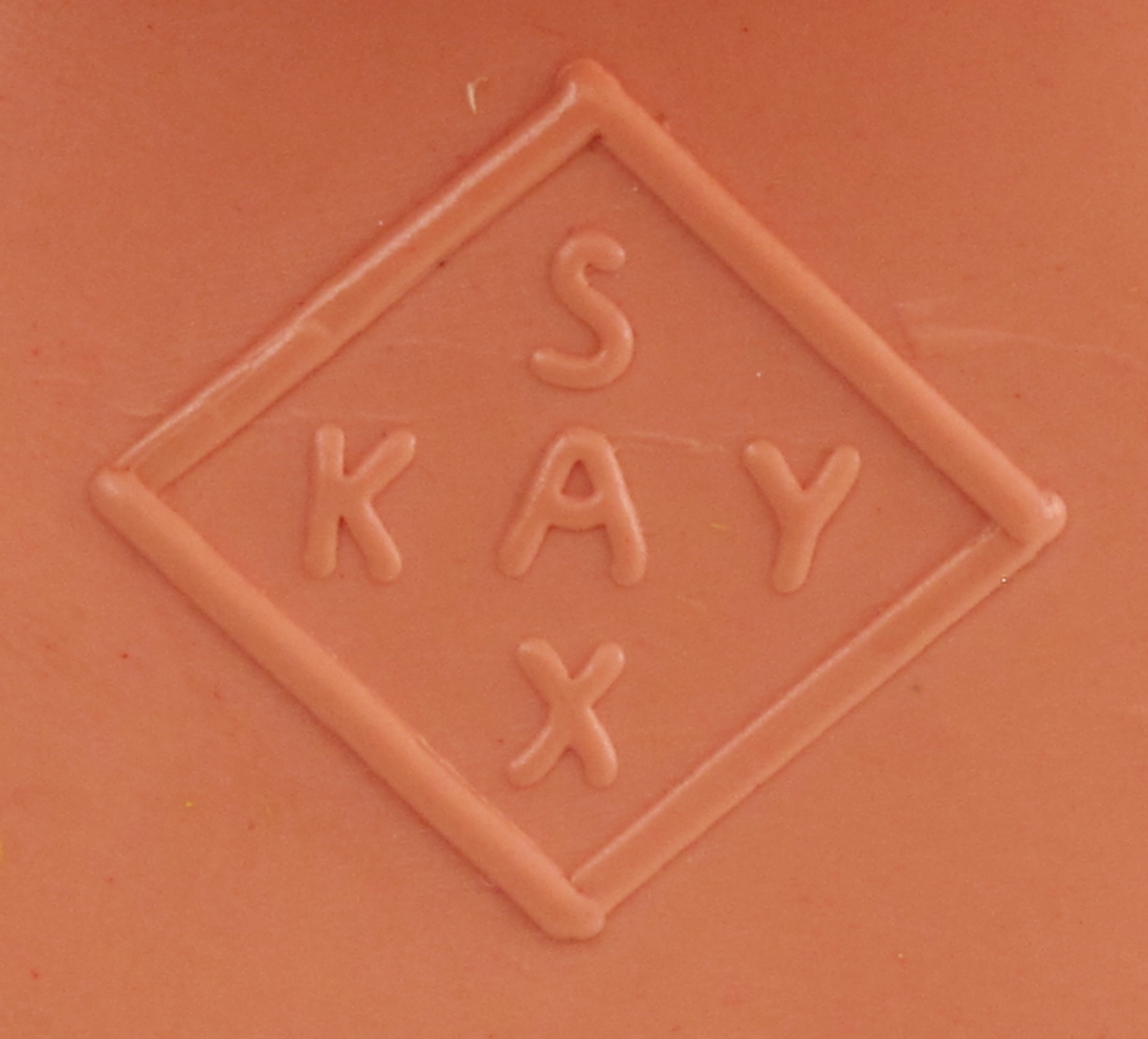 Dukkehode i celluloid. Øyer av innstøpt plast (?). Malte detaljer munn, øyebryn og,hår.  Hull i skulderpartiet for påsying av dukkekropp av tekstilt materiale.