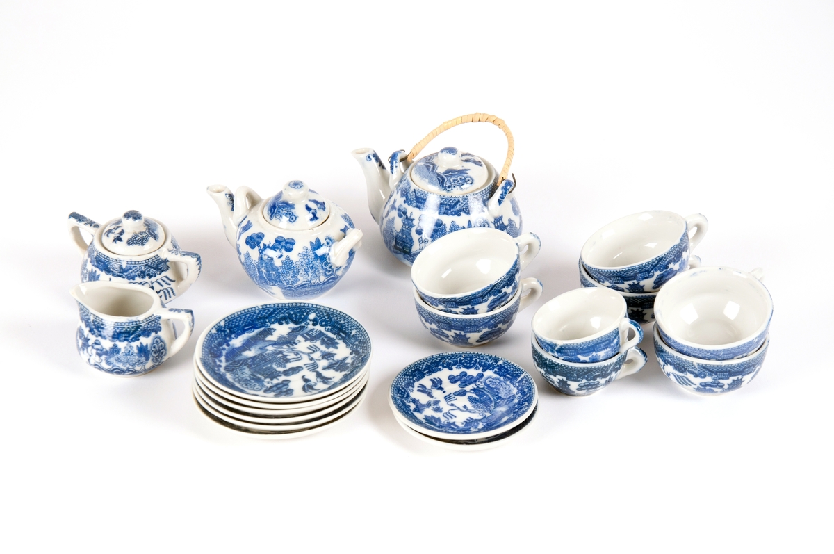 Dukkeservise i 12 deler; 6 tekopper og kanne, 2 kaffekopper og kanne, fløtemugge og sukkerskål. Dekoren har mønster i blått og hvitt; det populære "willow pattern" eller piletremønsteret.