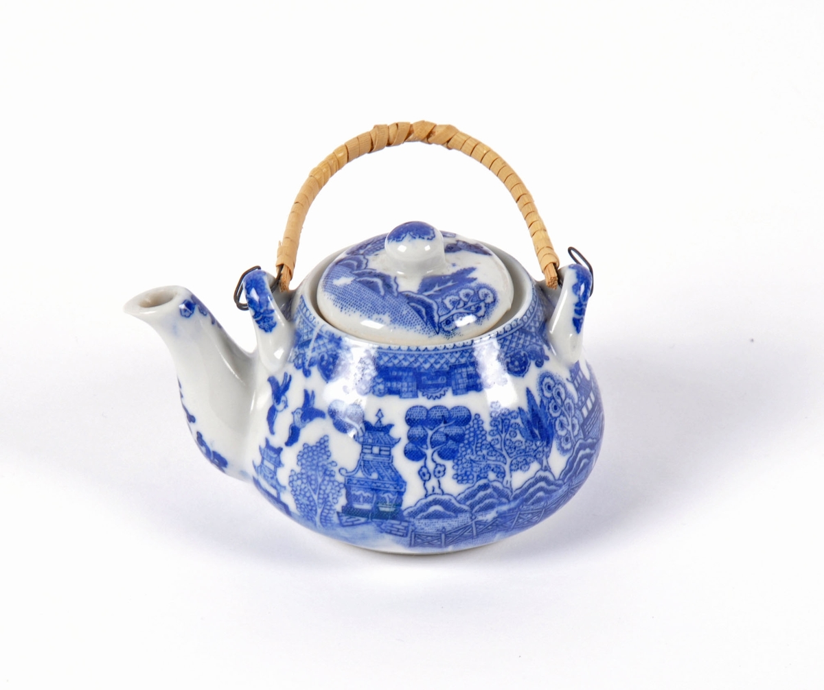 Dukkeservise i 12 deler; 6 tekopper og kanne, 2 kaffekopper og kanne, fløtemugge og sukkerskål. Dekoren har mønster i blått og hvitt; det populære "willow pattern" eller piletremønsteret.