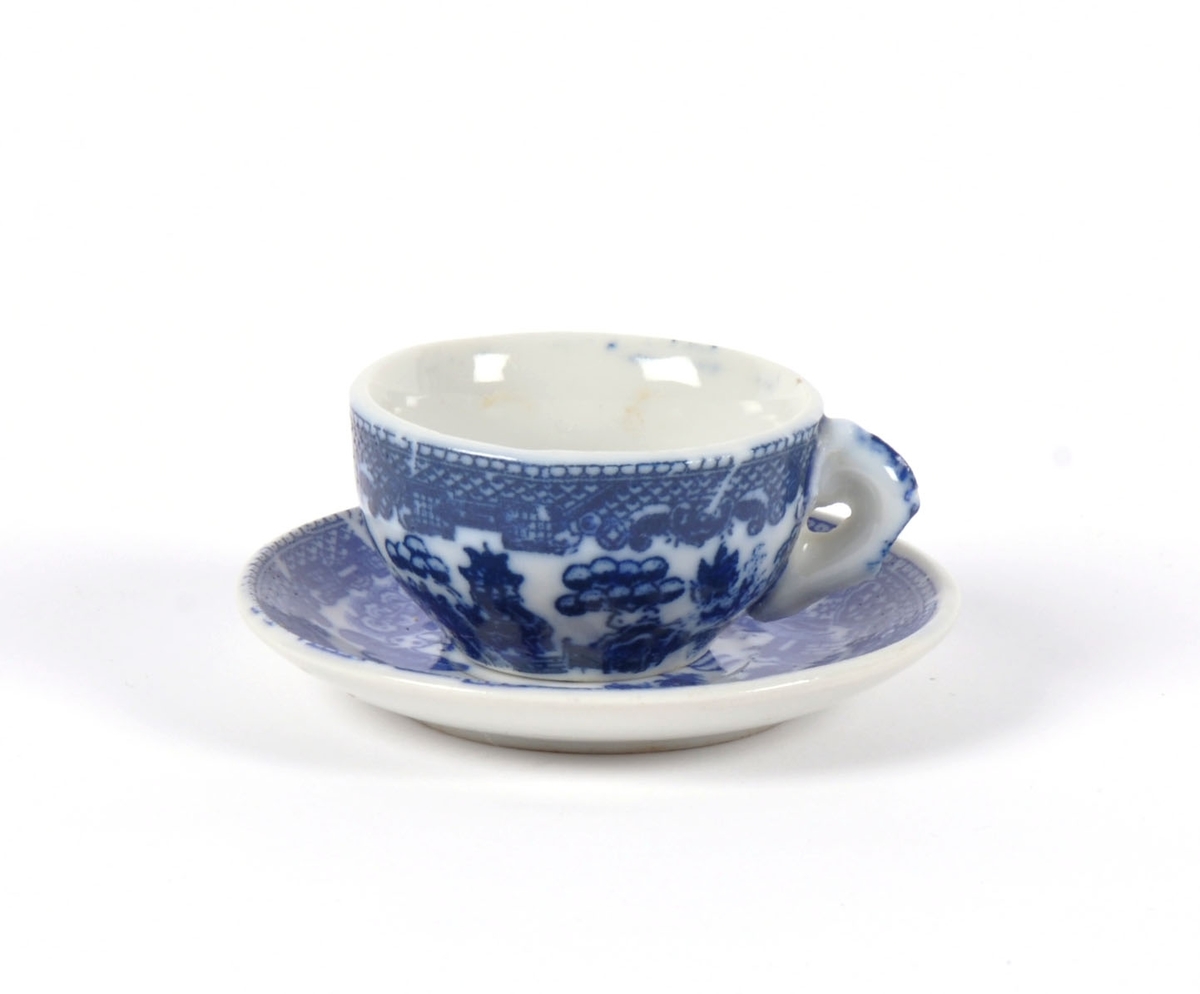 Dukkeservise i 12 deler; 6 tekopper og kanne, 2 kaffekopper og kanne, fløtemugge og sukkerskål. Dekoren har mønster i blått og hvitt; det populære "willow pattern" eller piletremønsteret.