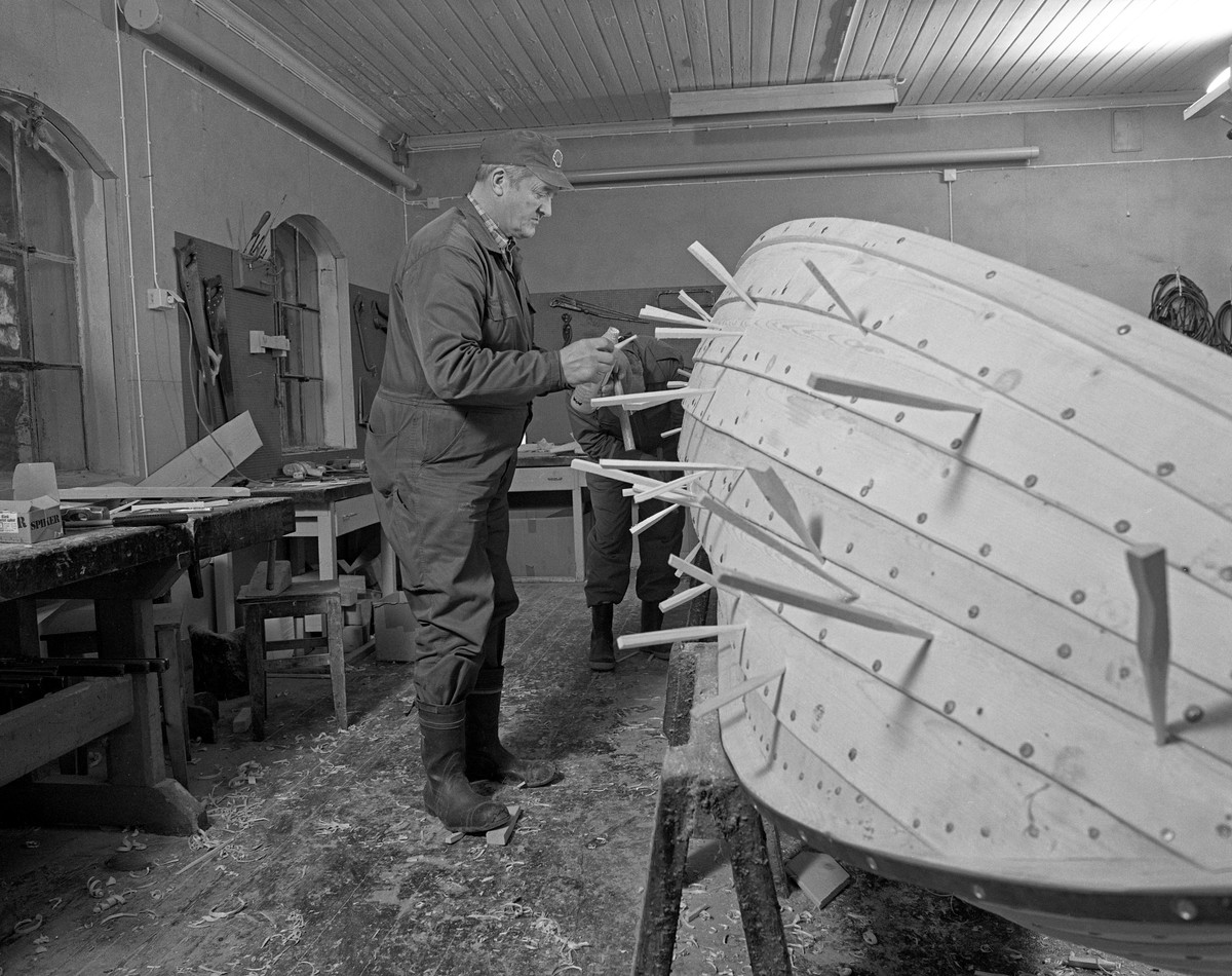 Bygging av fløterbåt («Flisa-båt») i Glomma fellesfløtingsforenings verksted på Breidablikk i Åsnes i november 1984. På dette fotografiet ser vi Lars Bernhard Olastuen banke treplugger inn i bordgangene. At dette var nødvendig skyldtes antakelig at det var svartkvist i materialene. Dette er kvistved som var død, og følgelig ikke lenger hadde noe vekstsamband med omkringvoksende stammeved da treet ble hogd. Det innebar fare for lekkasjer. Båtbord skulle derfor, i likhet med tønnestav, helst ikke ha for mye svartkvist.