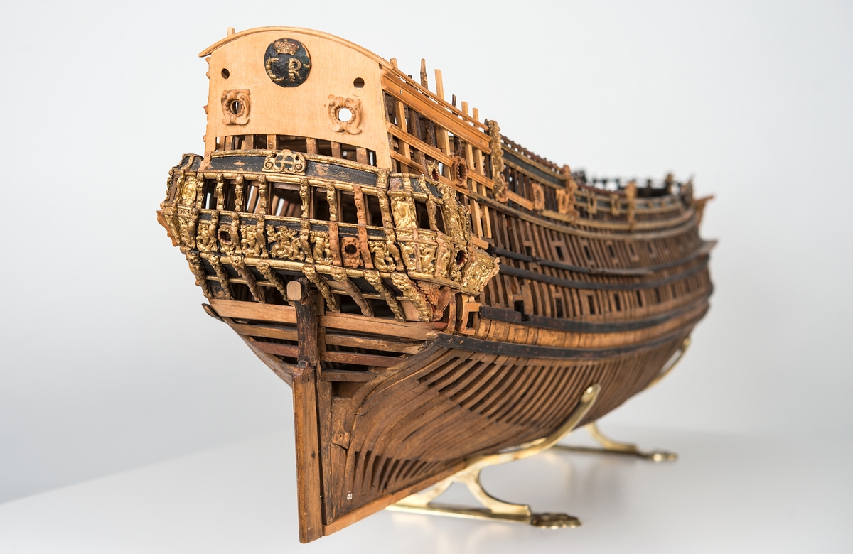 This unplanked model of a three-decker can be dated to c. 1660 and is one of the world's oldest models of a warship. Although not definitively identified, recent research links it to the Swedish ship *Riksäpplet*, designed by the English master shipwright Francis Sheldon and launched in 1661.     
The model was possibly made for Sheldon, who came to Sweden in 1659. He was one of a number of English shipwrights employed by the Swedish crown during the period. Previously, most Swedish warships had been built in the Dutch style.

From around 1660, the English Royal Navy’s administrators commissioned models that were accurately detailed and true to scale. These miniatures, which came to be called Navy or Admiralty Board models, had an unplanked lower hull to emphasise the shape of the underwater body. 

The model was restored by rear-admiral Jacob Hägg in the late 1890s. Missing parts have been reconstructed using lighter coloured wood.

3D model produced by Adam de Kaminski and Vasilis Haroupas for SMTM, 2023
