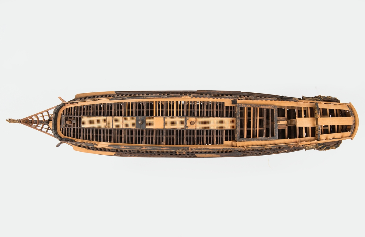 This unplanked model of a three-decker can be dated to c. 1660 and is one of the world's oldest models of a warship. Although not definitively identified, recent research links it to the Swedish ship *Riksäpplet*, designed by the English master shipwright Francis Sheldon and launched in 1661.     
The model was possibly made for Sheldon, who came to Sweden in 1659. He was one of a number of English shipwrights employed by the Swedish crown during the period. Previously, most Swedish warships had been built in the Dutch style.

From around 1660, the English Royal Navy’s administrators commissioned models that were accurately detailed and true to scale. These miniatures, which came to be called Navy or Admiralty Board models, had an unplanked lower hull to emphasise the shape of the underwater body. 

The model was restored by rear-admiral Jacob Hägg in the late 1890s. Missing parts have been reconstructed using lighter coloured wood.

3D model produced by Adam de Kaminski and Vasilis Haroupas for SMTM, 2023
