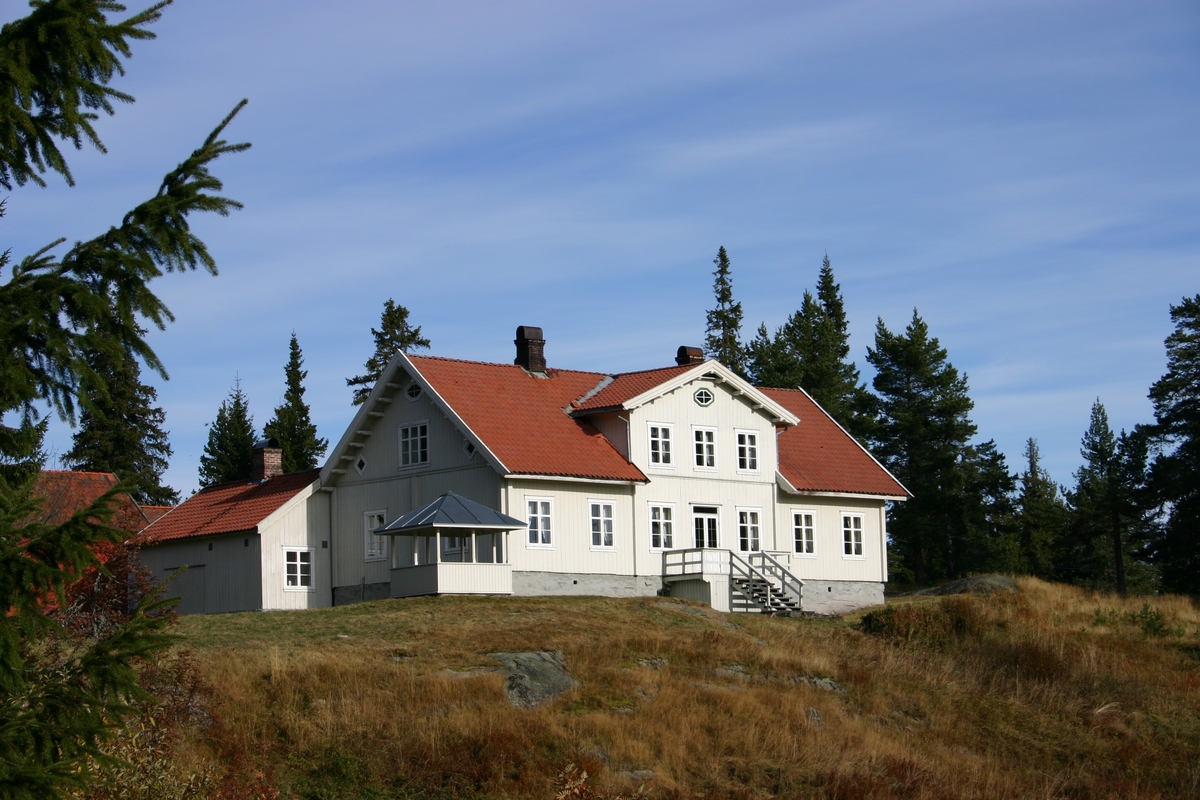 Laftet bygning i to etasjer med kjeller. Tegl på taket.