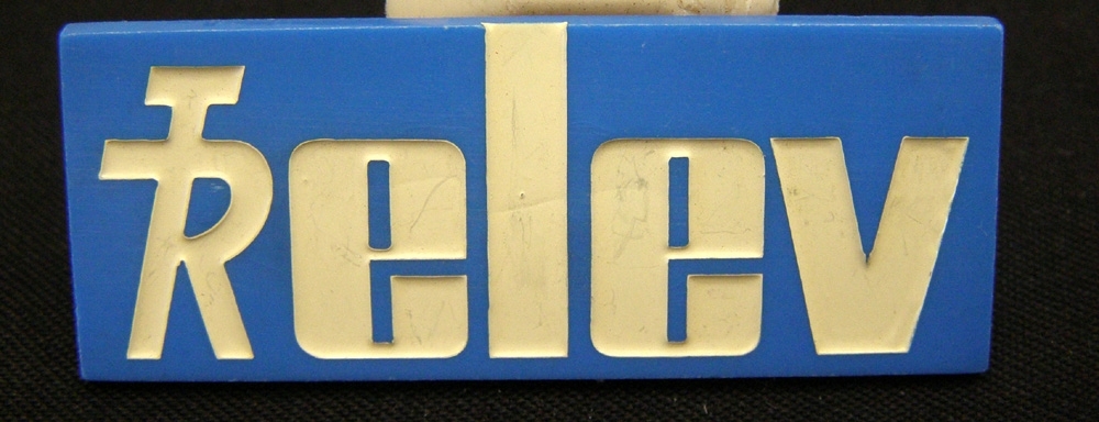Bröstbricka av blå plast med vit text: "elev" tillsammans med TR:s logotyp.