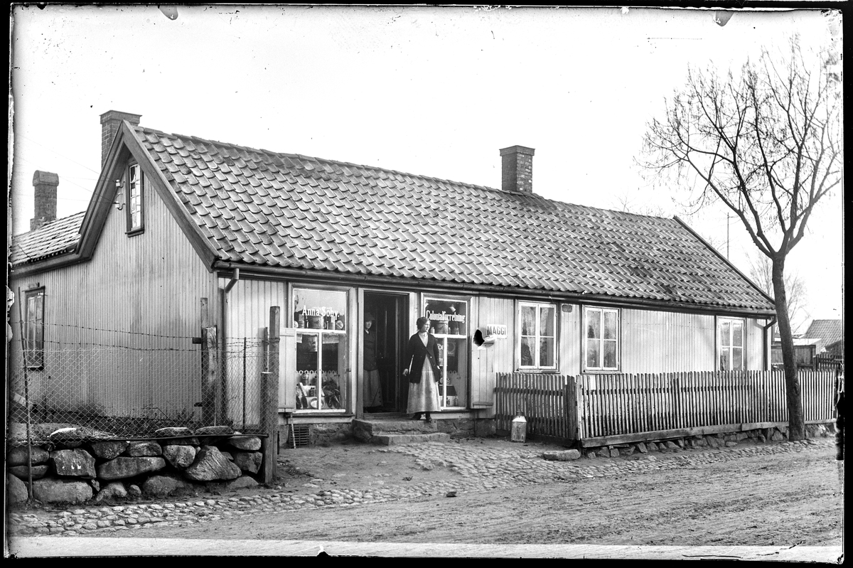 Klostergata 38 i Moss, tidligere Klostergata 35. 
Anna Søby Colonialforretning. Reklame for Maggi, ifølge  Adressekalender Moss 1911-12.
To kvinner i døra. Kan være Anna Johanne Johansen f. Søby 1875 i Rygge med bostedadresse Klostergata 35 ifølge Folketellinga for Moss 1914.
Annonse i Moss Socialdemokrat 14.10.1916: Prima nysprængt Faarekjød..... Anna Søby, Klostergt."