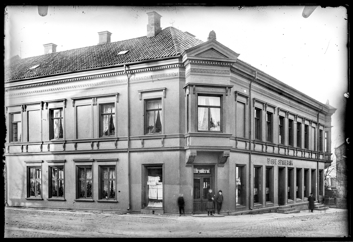 Kongens gate 21 i Moss, forretningen til Ida Brynildsrud. Handlende Kortevare & Industriforretning.
Kongens gate 21 i Moss,  Rygge Sparebank. Gateadresse for sparebanken og Brynildsrud var  Kongens gate 21  ifølge Adressebok for Fredrikshald, Fredrikstad, Moss, Sarpsborg 1911-12.
Denne butikken sees også på bilde nr 014-076