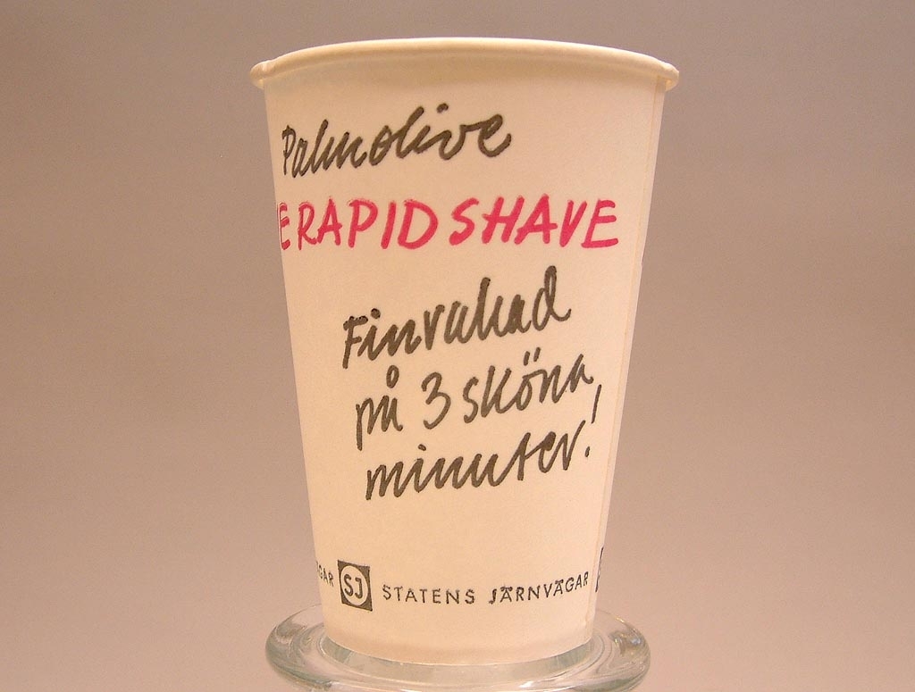Vit pappersmugg med svart och röd text.
Palmolive
Rapid shave
Finrakad på 3 sköna minuter.
Statens Järnvägar med SJ-logga.