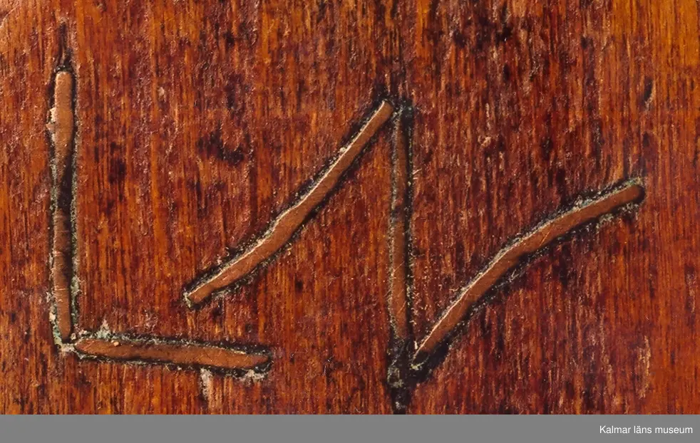 KLM 6626. Raklåda av björk. Raklådan skuren ur ett stycke. Skjutlock av bok. Lock och långsidor ornerade med karvsnittsrosetter och virvelhjul. På ena gaveln inskuret ANO 1781, på den andra ett LN 52, (LN ihopskriver). I bottens undersida inslagna mässingsstift bildande initialerna LN. Lådan fernissad i senare tid.