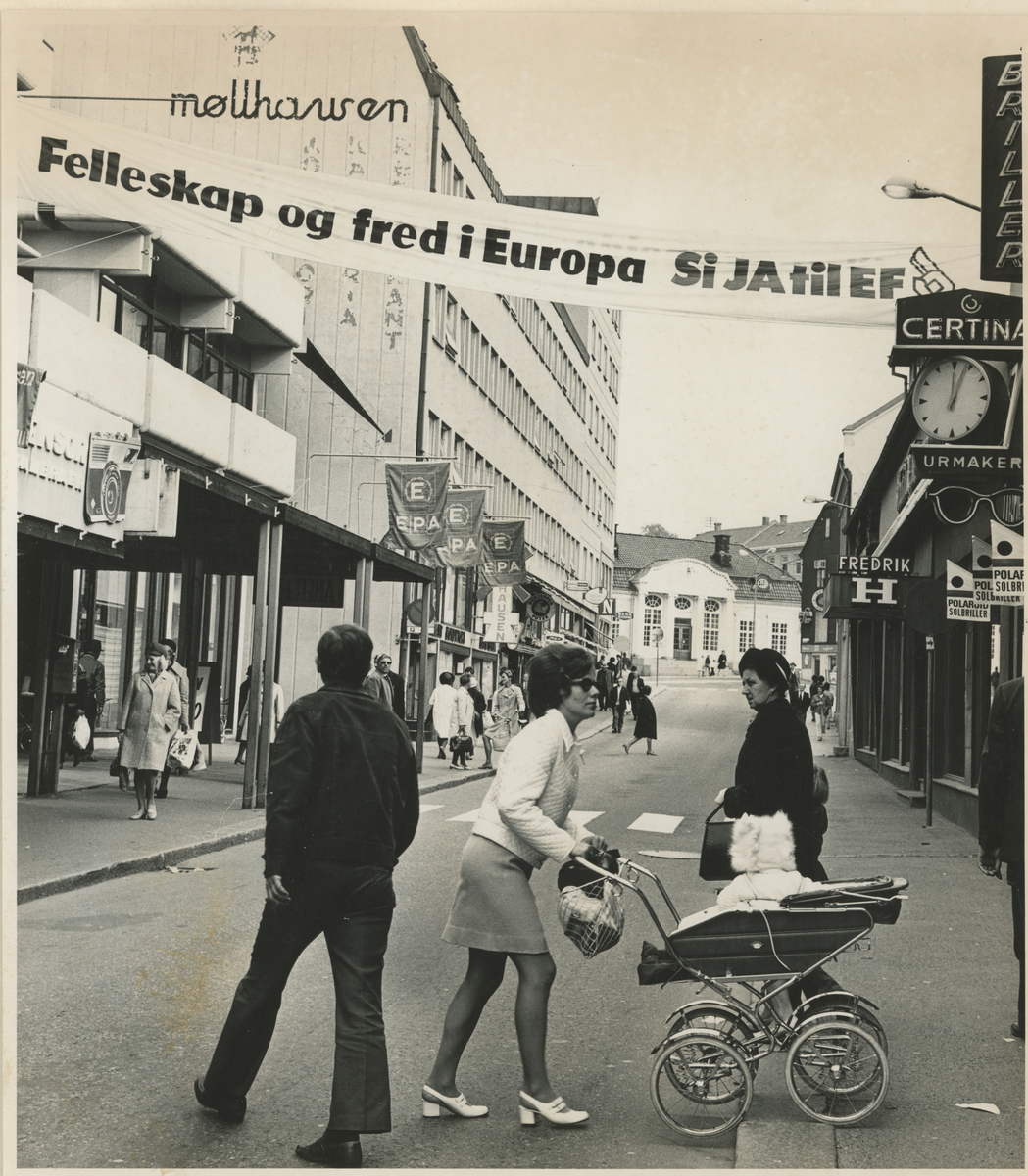 Bilde 1:
Fotograf har stått midt i Dronningens gate.
Detaljer: EPA til venstre og Møllhausen. På høyre side urmaker og klær.
Historikk: Banner: Ja til EF (EU). Resultat av valget ble NEI.

Bilde 2:
Fotograf har stått ved krysset Ibsens gate.
Detaljer: Arbeidere, folk, butikker.
Historikk: Det legges kantstein som skulle markere enveiskjøring.