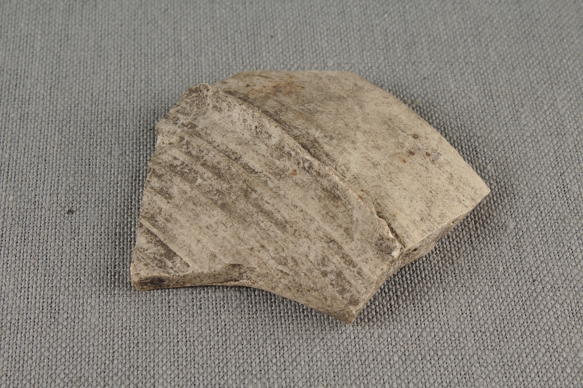 Skärva av drejat rhenskt stengods med ribbad dekor. Fragment från övre delen av ett kärl.