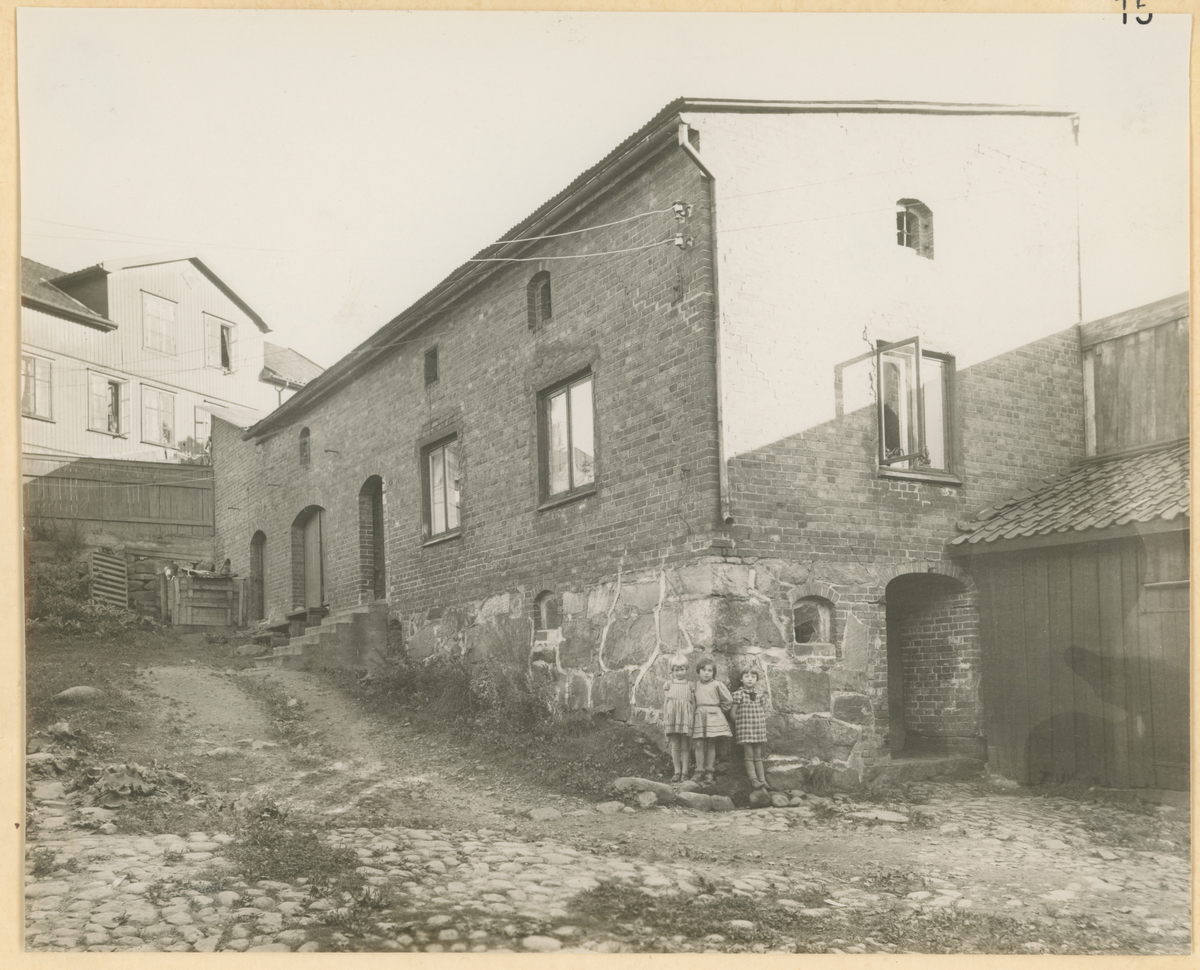 Ca. 1920. Fotograf har stått i gårdsrommet.
Detaljer:	Murbygning på eiendommen til Kongens gate 12. Barn. Bjerget 21 i bakgrunnen.
Historikk: Murgården fungerte som fengsel i en periode. Revet i 1960.