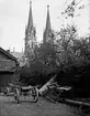 GÅRDSMILJÖ MED HÄSTANSPÄND ARBETSVAGN I BAKGRUNDEN DOMKYRKAN.