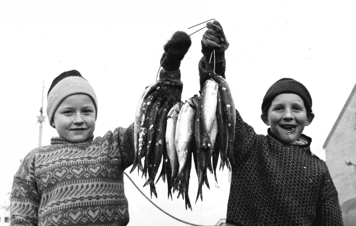 To gutter med sild tredd på en strenghank.