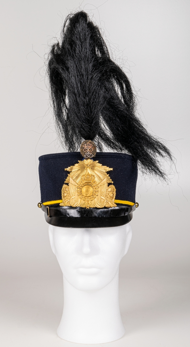 Mössa, uniformsmössa, blå med stor mässingsbricka, lilla riksvapnet omgivet av lejon, flaggor och med kungl. krona ovanför samt 5-uddig stjärna med strålar. Överst plymfäste med tagelplym. M/1899.