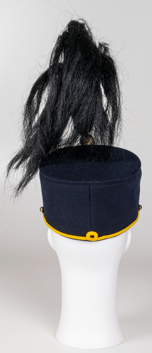 Mössa, uniformsmössa, blå med stor mässingsbricka, lilla riksvapnet omgivet av lejon, flaggor och med kungl. krona ovanför samt 5-uddig stjärna med strålar. Överst plymfäste med tagelplym. M/1899.