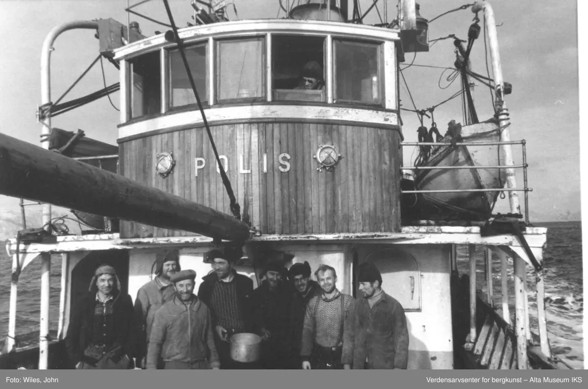 Gruppebilde av mannskapet på M/S Polis. 8 av dem er nede på dekk med muligens skipperen? øverst i styrhuset å lurer i vinduet.
Navn på mennene ønskes.