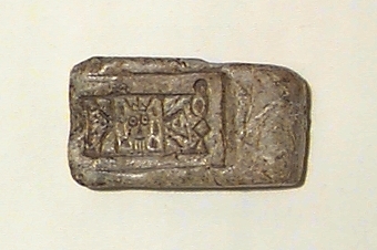 På ena bredsidan streckfigurer (bl.a. ett ansikte med en krona), på den motsatta sidan en hemisfärisk urgröpning. Även en oval urgröpning på ena smalsidan. I huvudliggaren upptagen som gjutform för rektangulärt spänne.